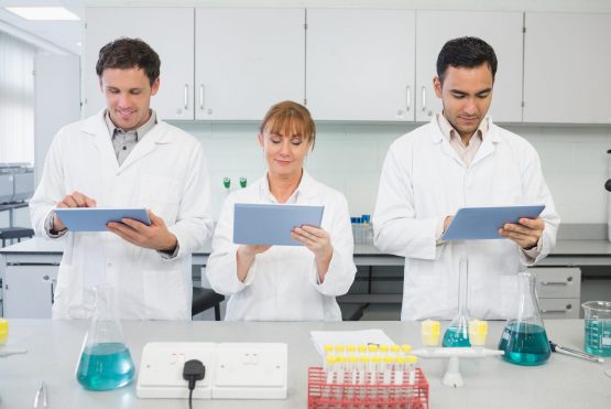 Group of serious scientists using tablet PCs in the laboratory